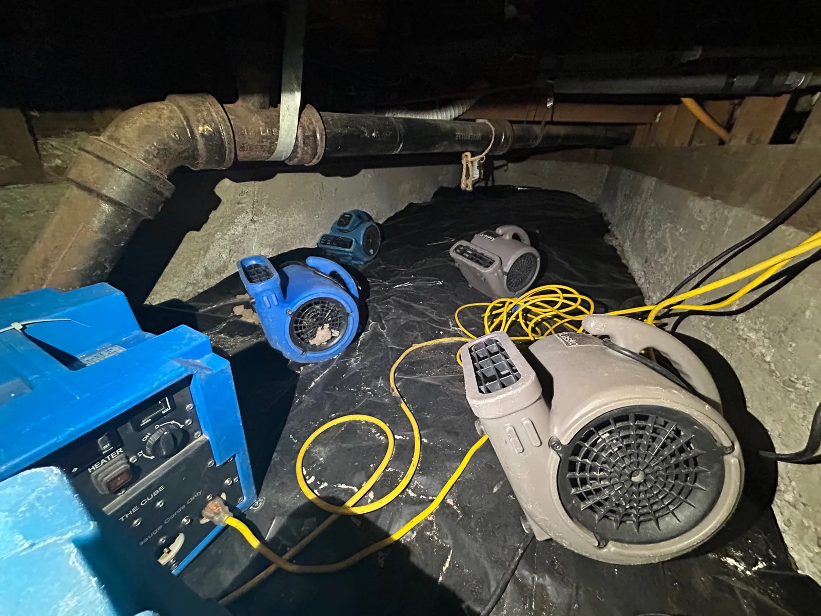 Air movers and a dehumidifier drying a crawl space after a sewage backup
